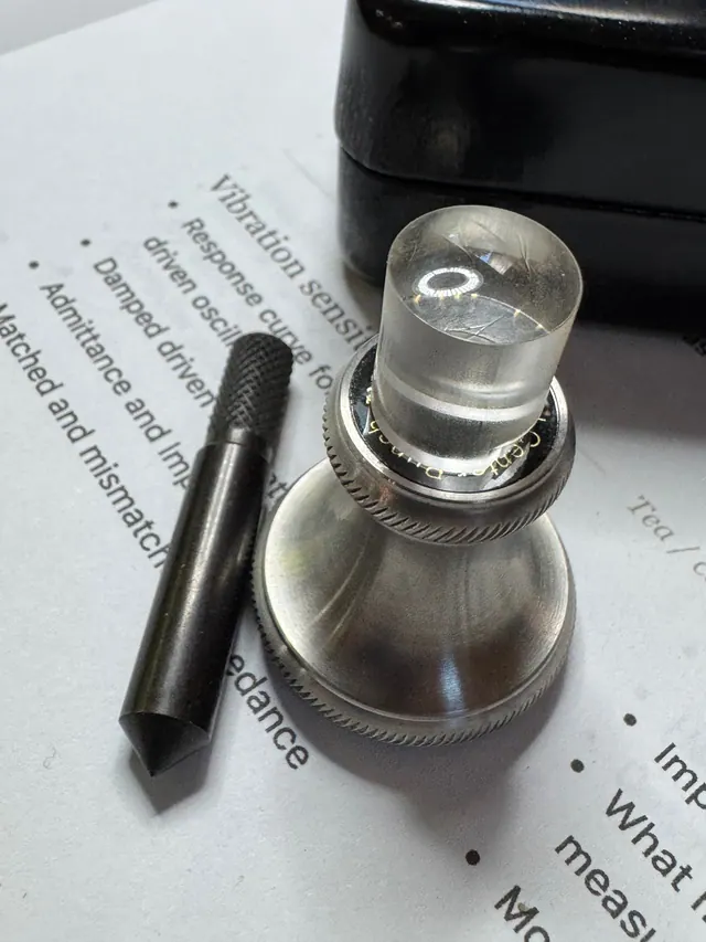 Tap-testing equipment sitting on a printed page about damping and impedance