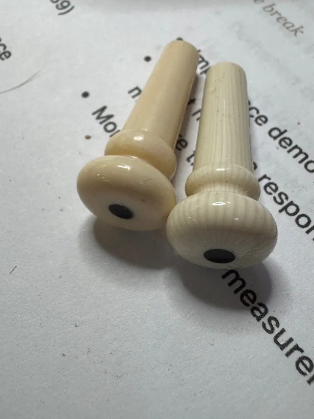 Two cream bridge pins on a page of notes about measurement and response