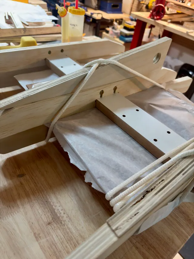 A shop-made rope clamping jig pressing a joint over parchment paper