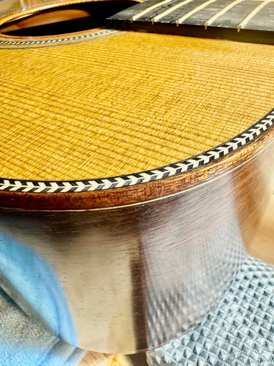 Close-up of a French polished guitar top, rosette, and glossy rosewood side