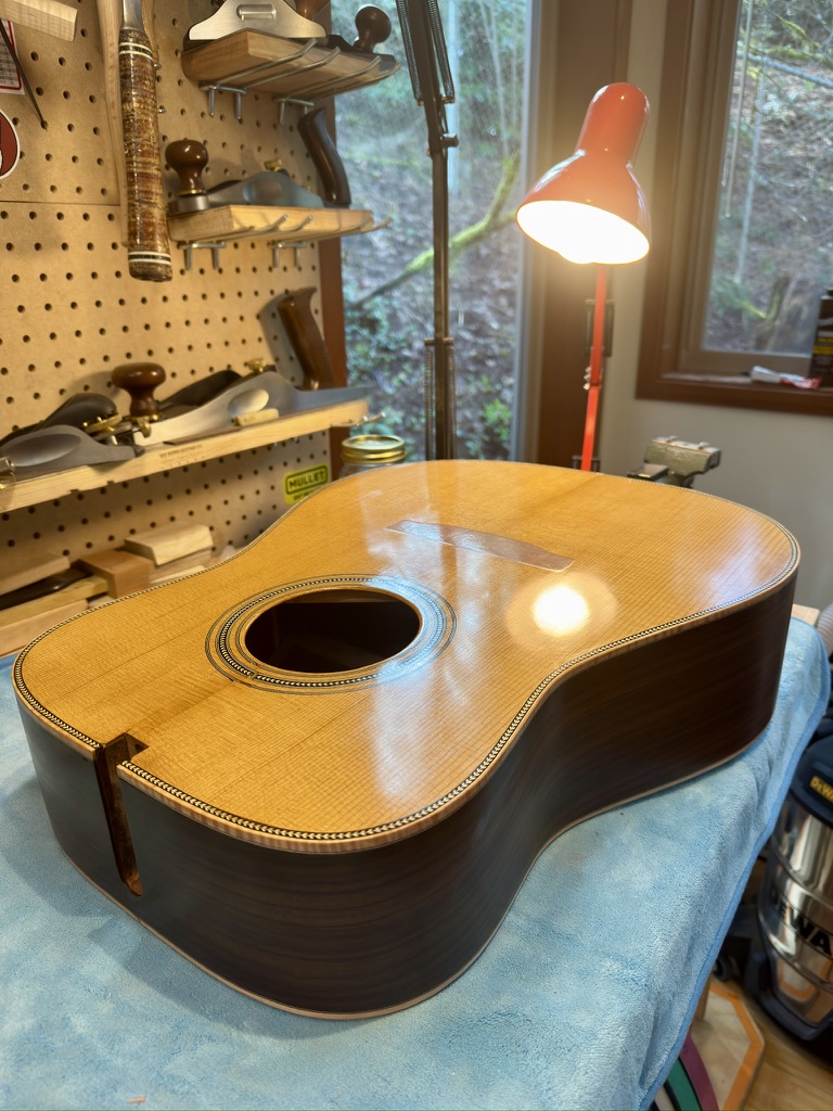 Spruce dreadnought top under shop lamp, herringbone binding and rosette detail