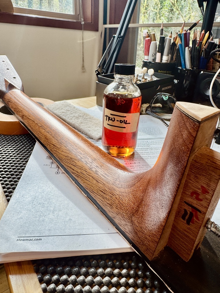 Mahogany neck oiled with Tru-Oil, bottle beside it on the bench